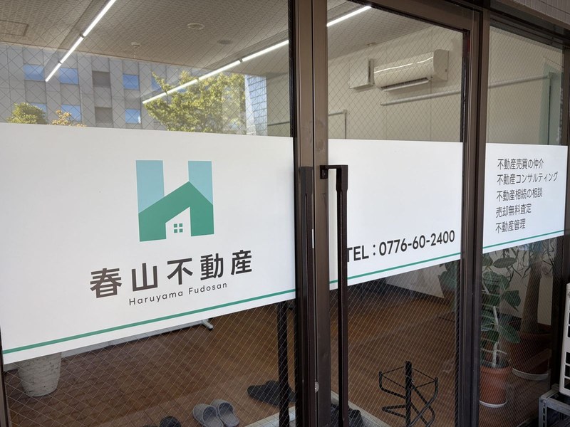 春山不動産事務所の入口ドアに掲げられた看板（福井市）